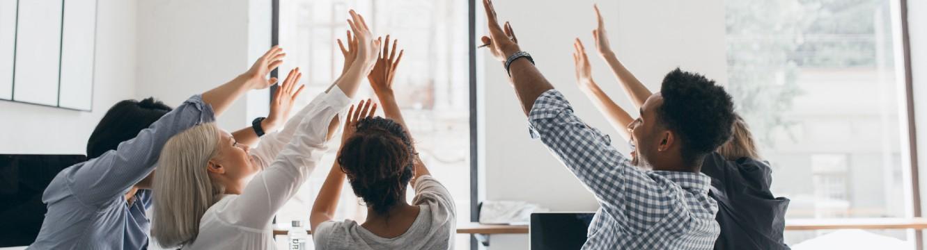 Une équipe de collaborateurs lèvent les mains dans la même direction